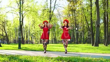 两位身着鲜艳服装的女舞者在阳光公园表演民族舞